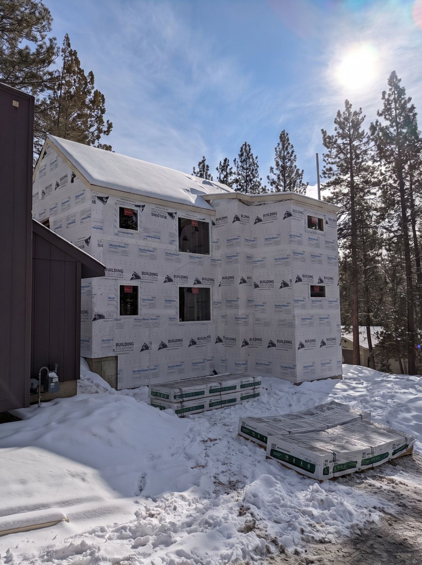 Two-story ADU sheathed and wrapped in weather barrier, dried in with snow on the ground