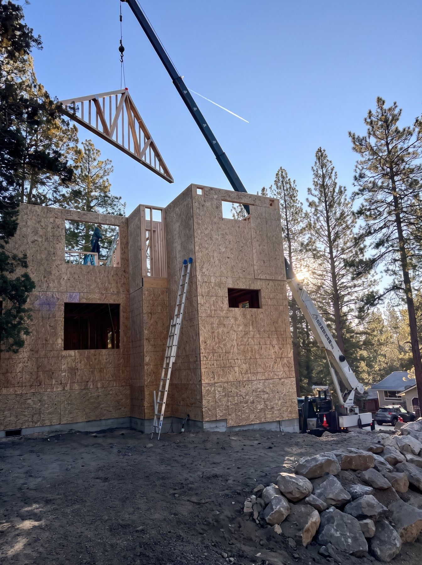 Roof trusses being set by crane on a sheathed two-story ADU